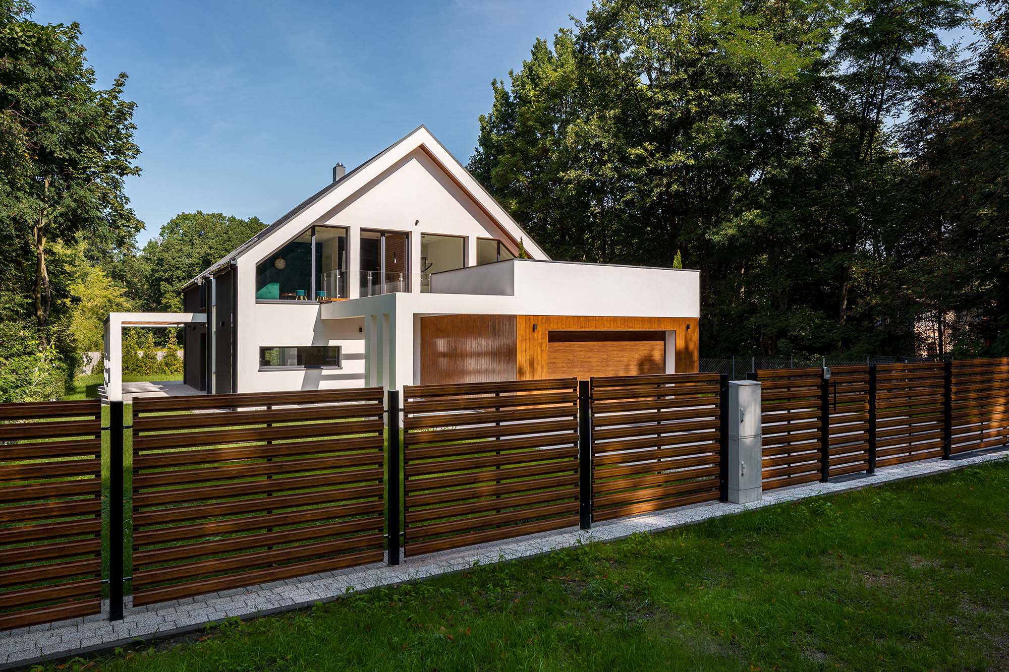 Ett modernt hus med vit fasad och garage i trä